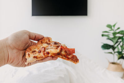 Close-up of hand holding pizza on table