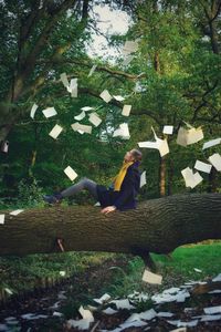 Woman sitting on tree trunk in park
