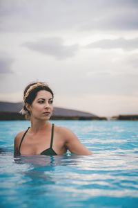 Woman in swimming pool against sea