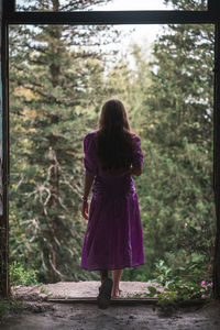 Rear view of woman standing in front of forest