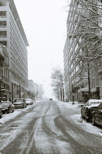 Snow covered road along buildings in winter