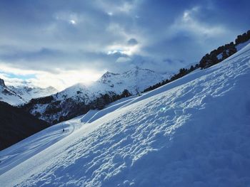 Scenic view of snow covered mountains against cloudy sky