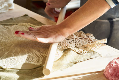 Midsection of woman rolling lace on dough at table