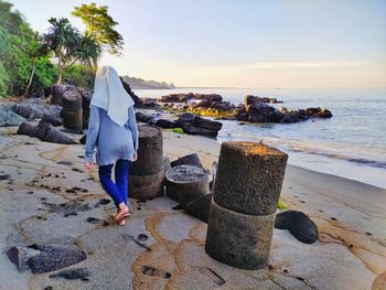 Rear view of a girl walking at beach against sky