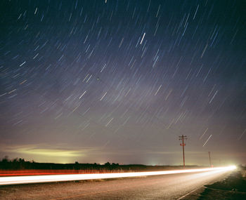 Light trails on road against sky at night