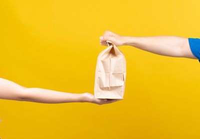 Midsection of woman holding paper against yellow background