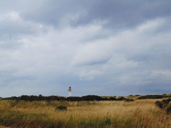 Lighthouse on field against sky