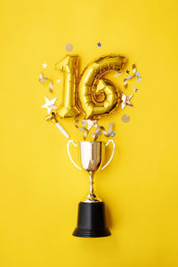 Directly above shot of trophy against yellow background