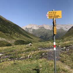 Road sign by mountains against sky