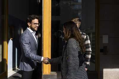 Male real estate agent doing handshake with clients in front of apartment