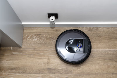 A modern robotic vacuum cleaner cleans the ceramic tiles in the bathroom next to the electric socket