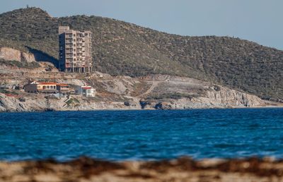 Scenic view of sea by buildings against sky