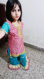 Portrait of cute girl standing against wall