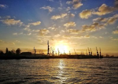 Silhouette sailboats in sea against sky during sunset