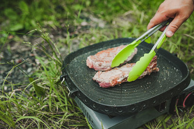Meat steak fried grill pan on gas stove open air, hand turns over potholders appetizing piece meat