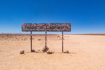 Information sign on desert against clear blue sky