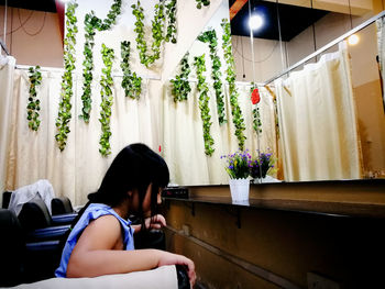 Woman sitting by potted plants at home