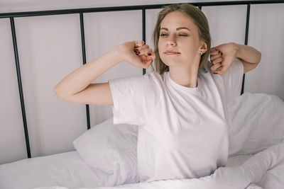 Portrait of young woman sitting on bed at home