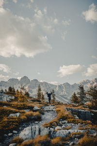 Rear view of woman dancing on mountain against sky during winter