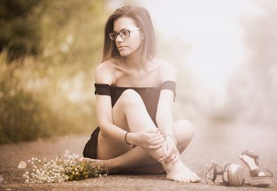 Full length of woman sitting on footpath