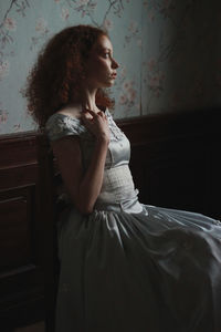 Young woman sitting on bed at home