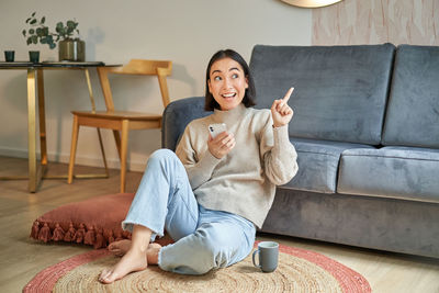 Portrait of young woman sitting on sofa at home