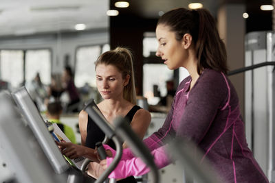 Fitness instructor assisting woman in exercising at gym