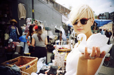Side view portrait of woman holding swan figurine while standing in market