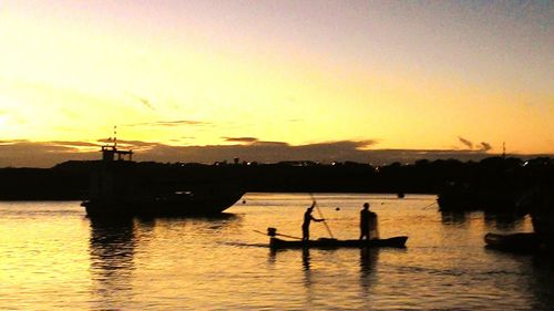 Boats sailing in sea at sunset