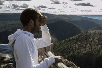 Side view of man standing at observation point against mountains