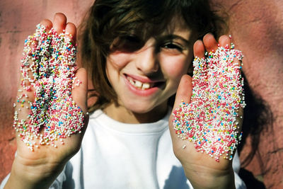 Portrait of smiling woman with multi colored candies on hand