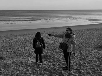 Women standing on beach by sea against sky