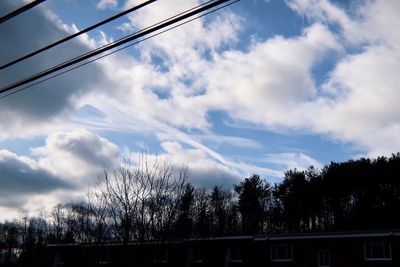 Low angle view of silhouette trees and buildings against sky