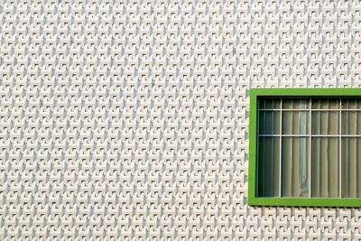 Green closed window on a modern 3d pattern facade with copy space