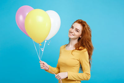 Portrait of smiling young woman against blue background