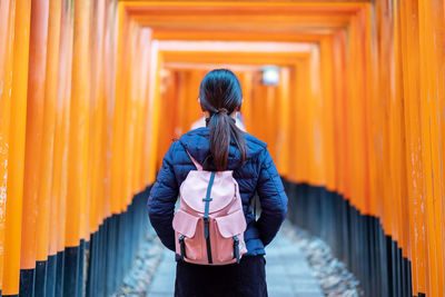 Rear view of woman standing by railing against building