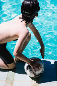 Shirtless boy playing with ball at poolside