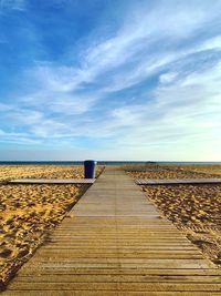 Boardwalk leading towards sea against sky