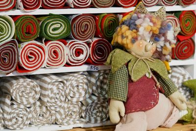 Close-up of stuffed toy by rolled up fabrics in shelves at store for sale