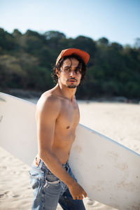 Full length of shirtless man standing at beach