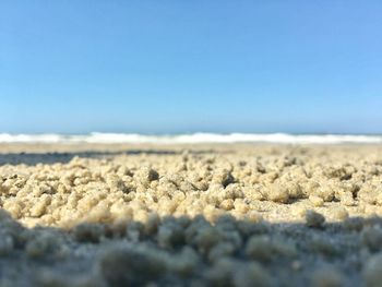 Surface level of sand against clear blue sky