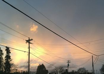 Low angle view of silhouette electricity pylon against sky