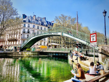 Arch bridge over river amidst buildings in city