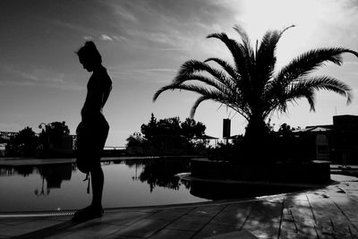 Silhouette woman by swimming pool against sky