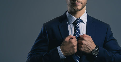 Midsection of man holding cigarette against white background