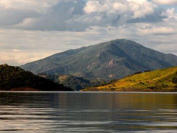 Scenic view of lake by mountains against sky