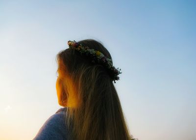 Low angle view of woman wearing wreath against sky