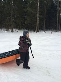 Full length of boy pulling snow tube on field during winter