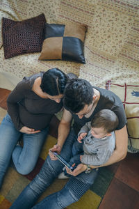 High angle view of father and daughter sitting on sofa at home