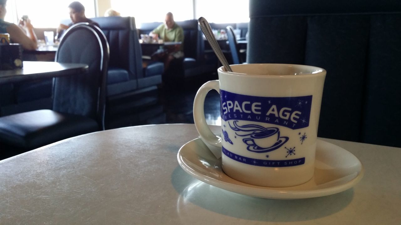 coffee cup, text, table, drink, indoors, western script, coffee - drink, communication, close-up, saucer, still life, food and drink, refreshment, cup, focus on foreground, no people, coffee, day, cafe, white color